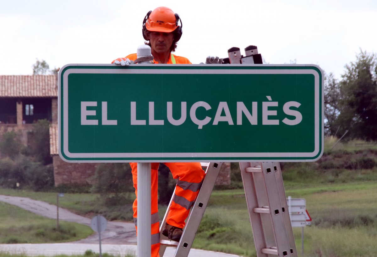 Un operari posant el cartell del Lluçanès