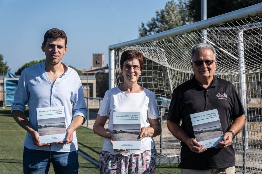 L'alcalde, Pol Barnils, i els autors del llibre Anna Soler i Jaume Soler, amb el llibre al camp de futbol