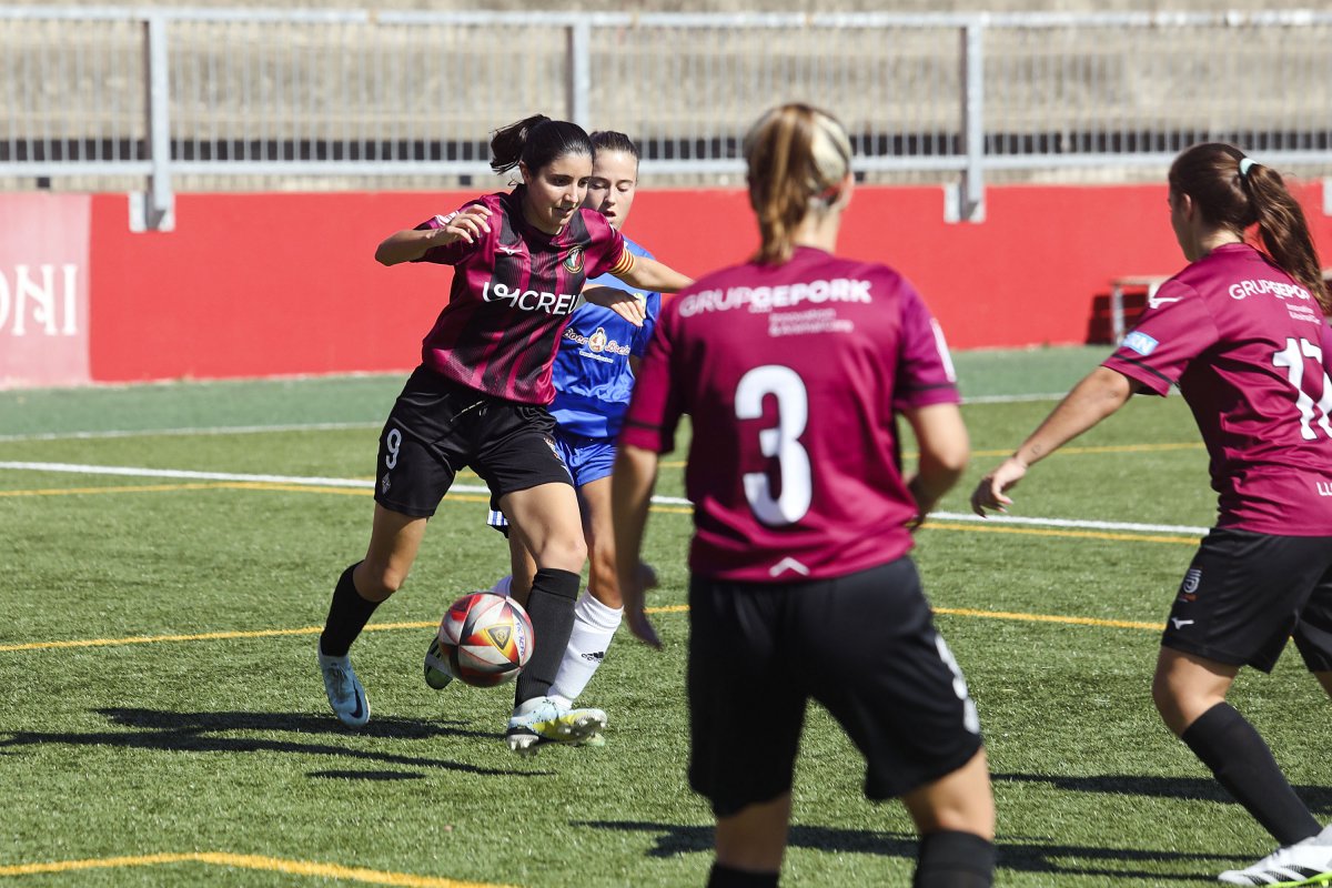 La capitana Núria Sala condueix una pilota pressionada per una jugadora rival