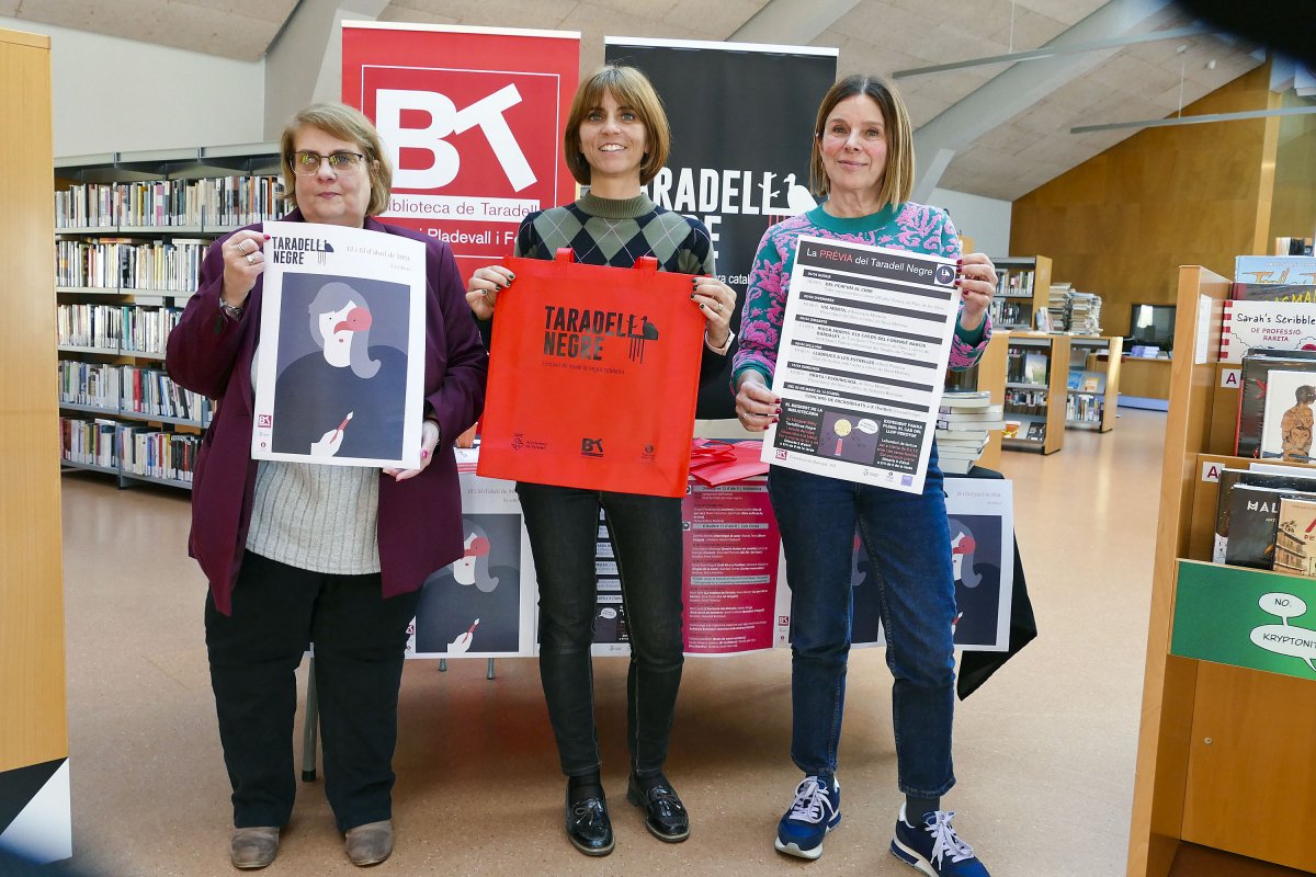 D’esquerra a dreta, Núria Martínez, Míriam Martínez i Eva Leucó a la biblioteca amb els cartells del festival