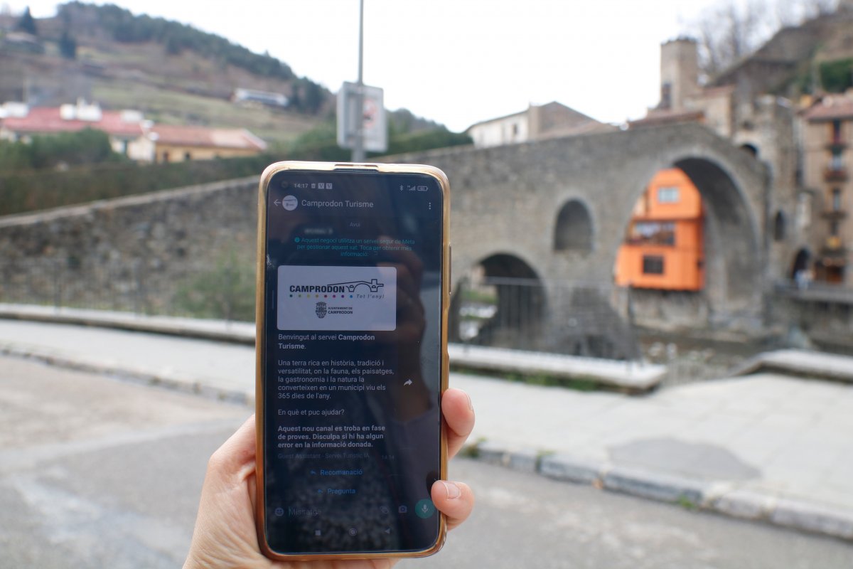 La guia, des del mòbil, oferint informació davant del característic pont de Camprodon