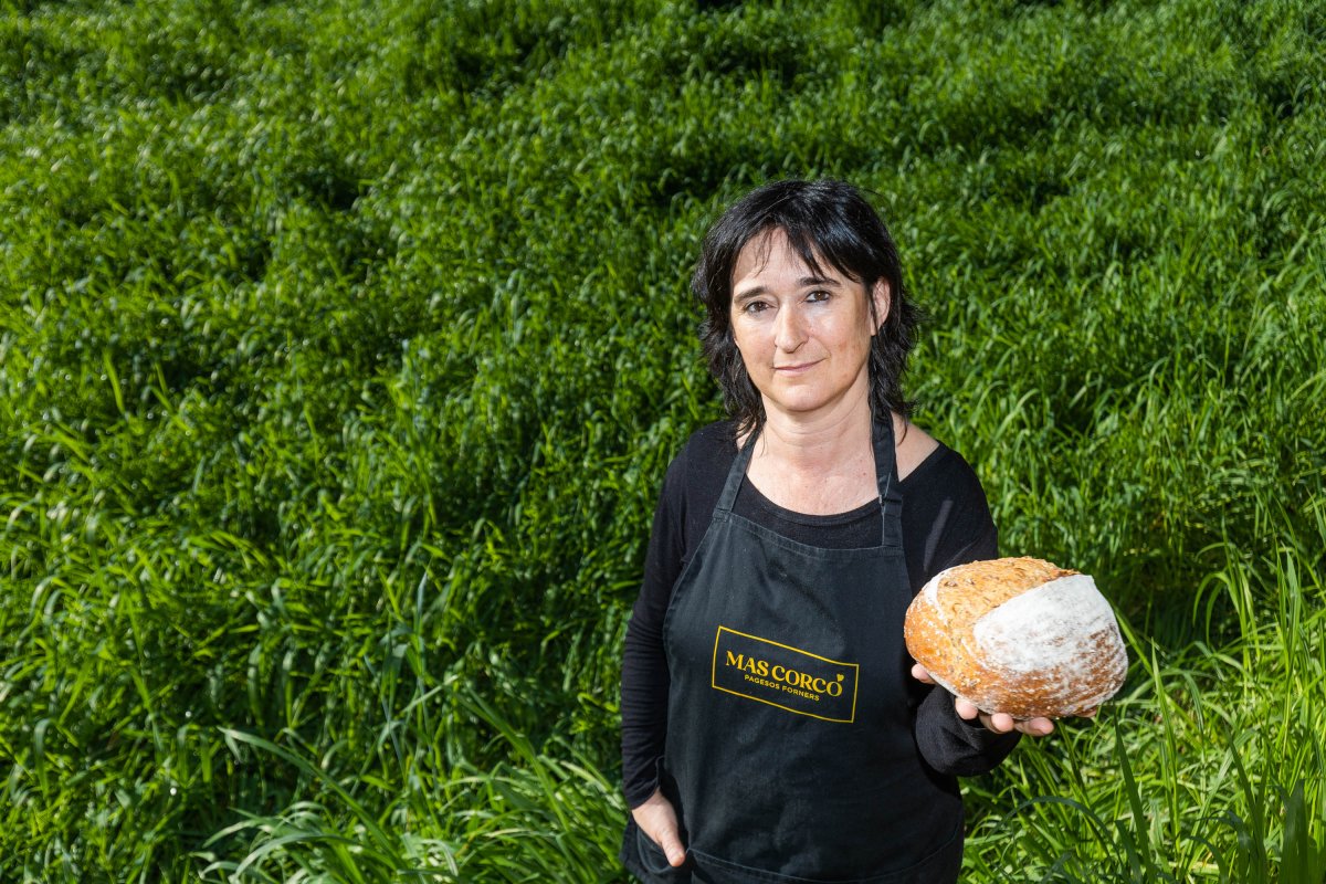 Montse Niubó, amb el pa de set llavors, envoltada del blat de la finca en fase de creixement: 