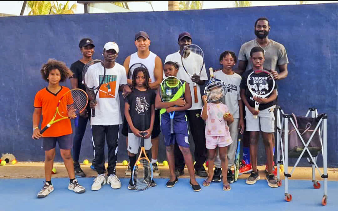 Carles Juan, amb samarreta blanca i sense mànigues, amb un dels grups d'infants a qui ensenya a jugar a tennis a Senegal