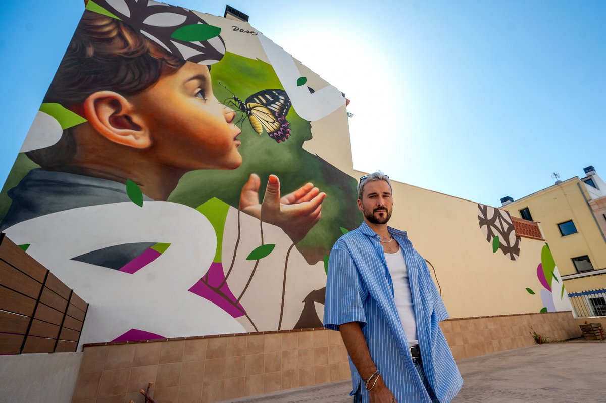 L'artista Dase davant del mural que es pot veure des dels carrers La Doma i Llerona