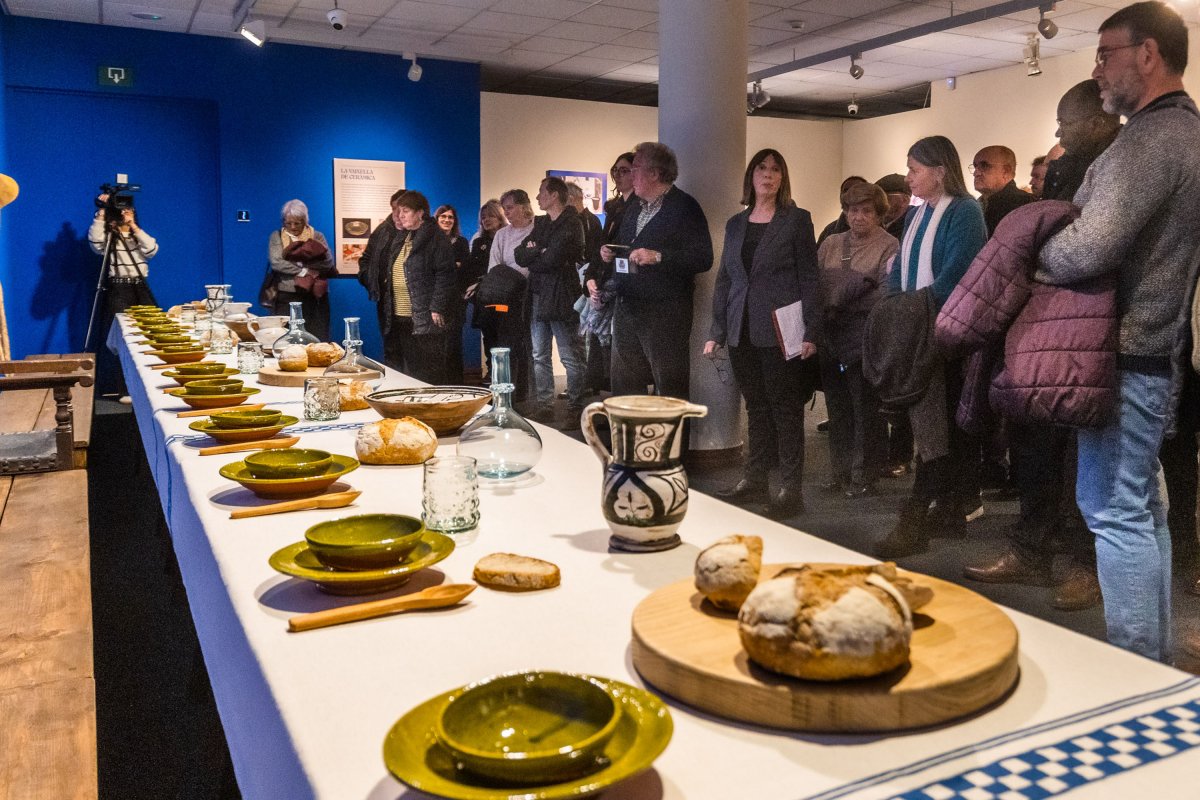Visitants davant la gran taula que és el centre de l'exposició