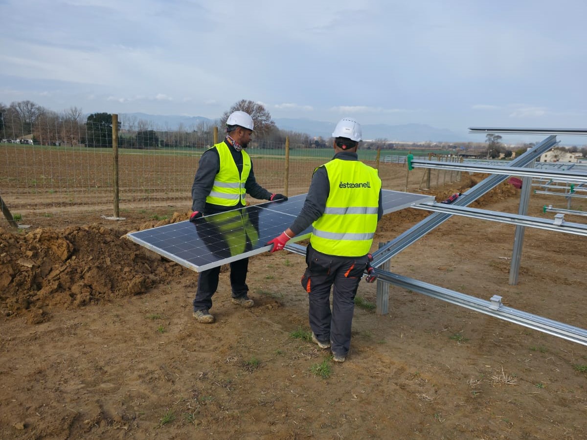 Dos operararis col·loquen una de les plaques del nou parc solar del Pla de la Font, a Vidreres