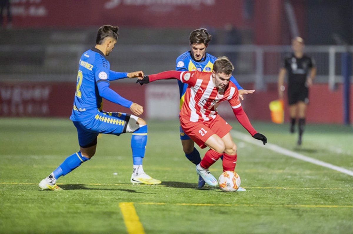 Nil Garrido intenta controlar la pilot davant de dos rivals durant el partit d'aquest dimecres a l'Hipòlit Planàs